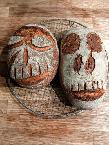 Two loaves of bread with faces carved into them are sitting on a cooling rack