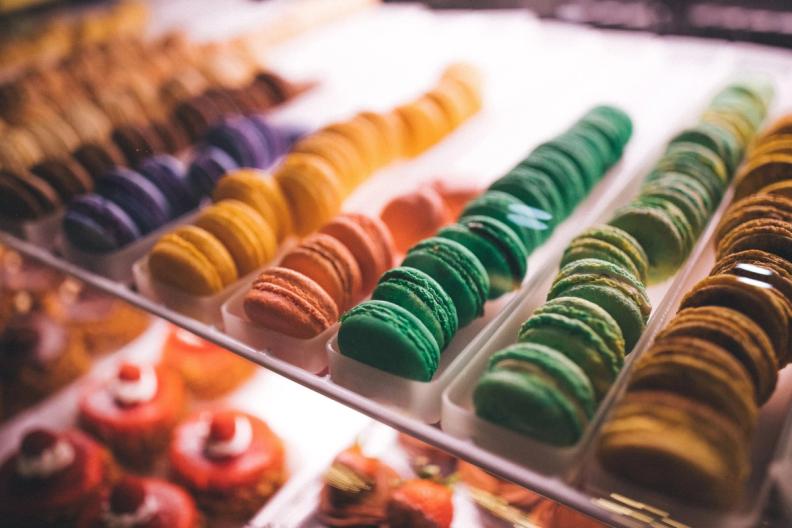 Rows of colorful macarons displayed in a glass case.