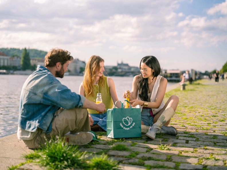 a group of people are sitting on the ground near a body of water .