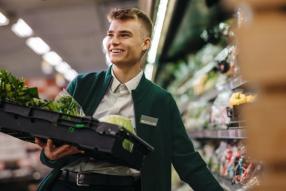 A male supermarket worker stocking groceries