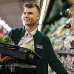 A male supermarket worker stocking groceries