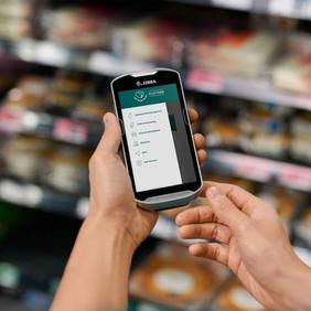 a person is holding a cell phone in their hand in a grocery store .
