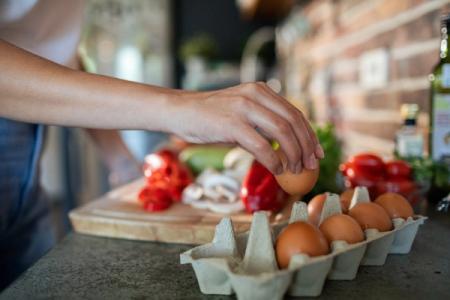 a person is cracking an egg into a carton of eggs .