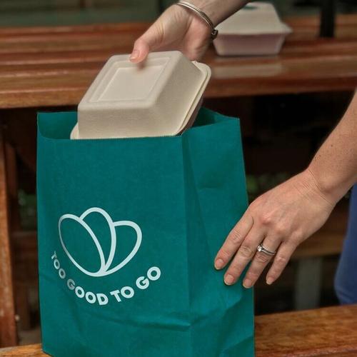 a person is putting a container into a bag that says `` too good to go '' .