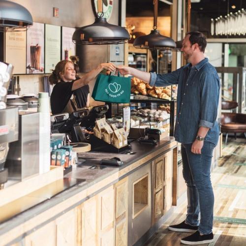 a man is getting a bag of food from a woman at a counter in a restaurant .