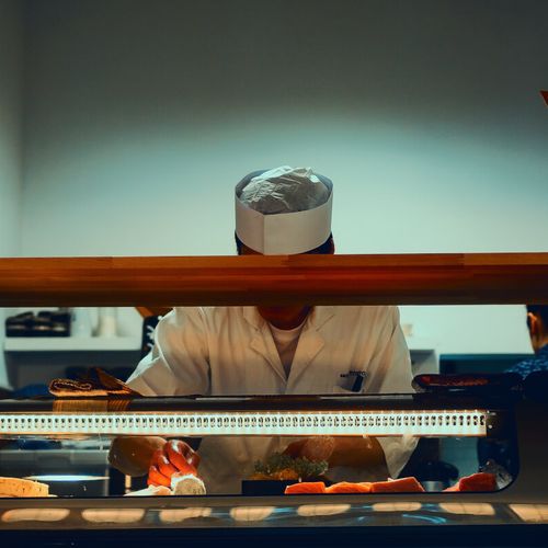a chef is preparing sushi in a restaurant kitchen .