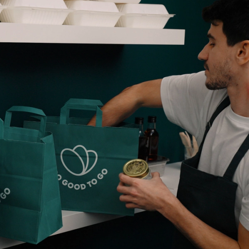a man holds a jar in front of a bag that says good to go