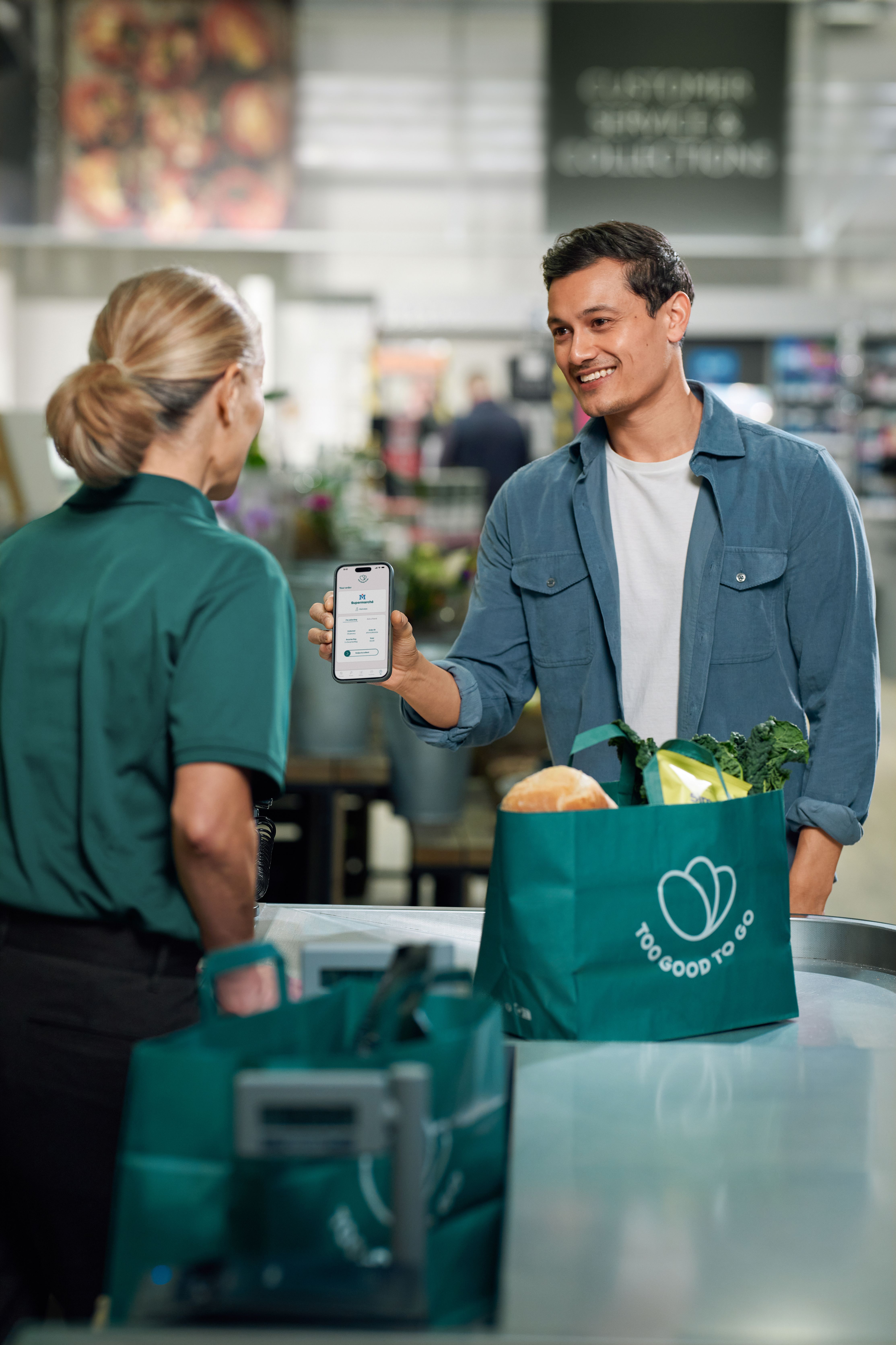 a man is holding a cell phone in front of a bag that says too good to go