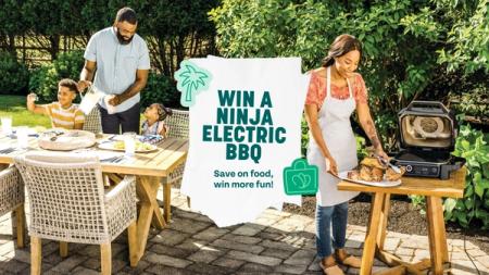 a woman is cooking food on a grill while a man and two children watch .