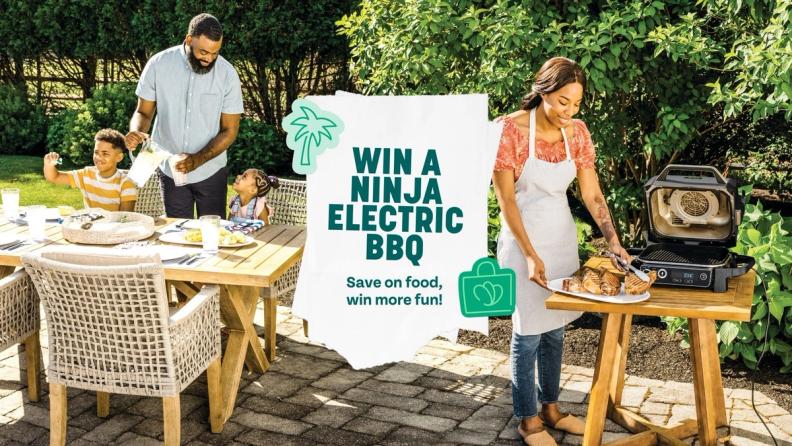 a woman is cooking food on a grill while a man and two children watch .