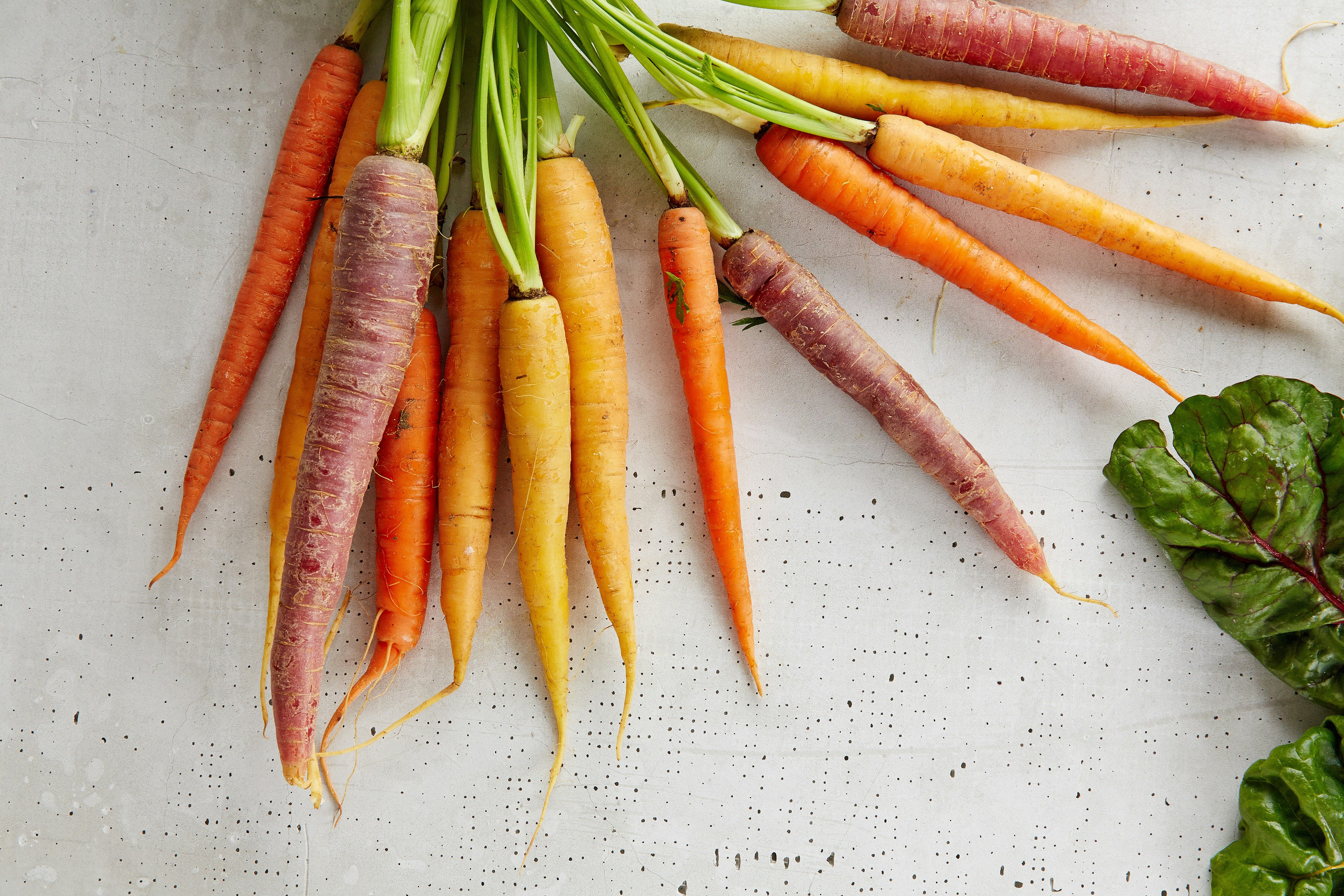 a bunch of carrots of different colors are sitting on a table .