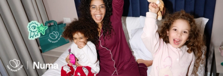 A joyful woman and two children in pajamas celebrate together on a bed, with "Too Good To Go" branding and "Numa" text.