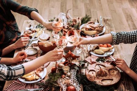 a group of people are sitting at a table eating food and drinking wine .