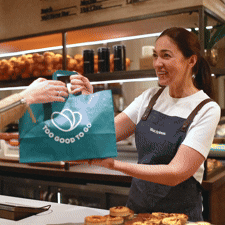 a woman is giving a bag of food to a customer in a bakery .