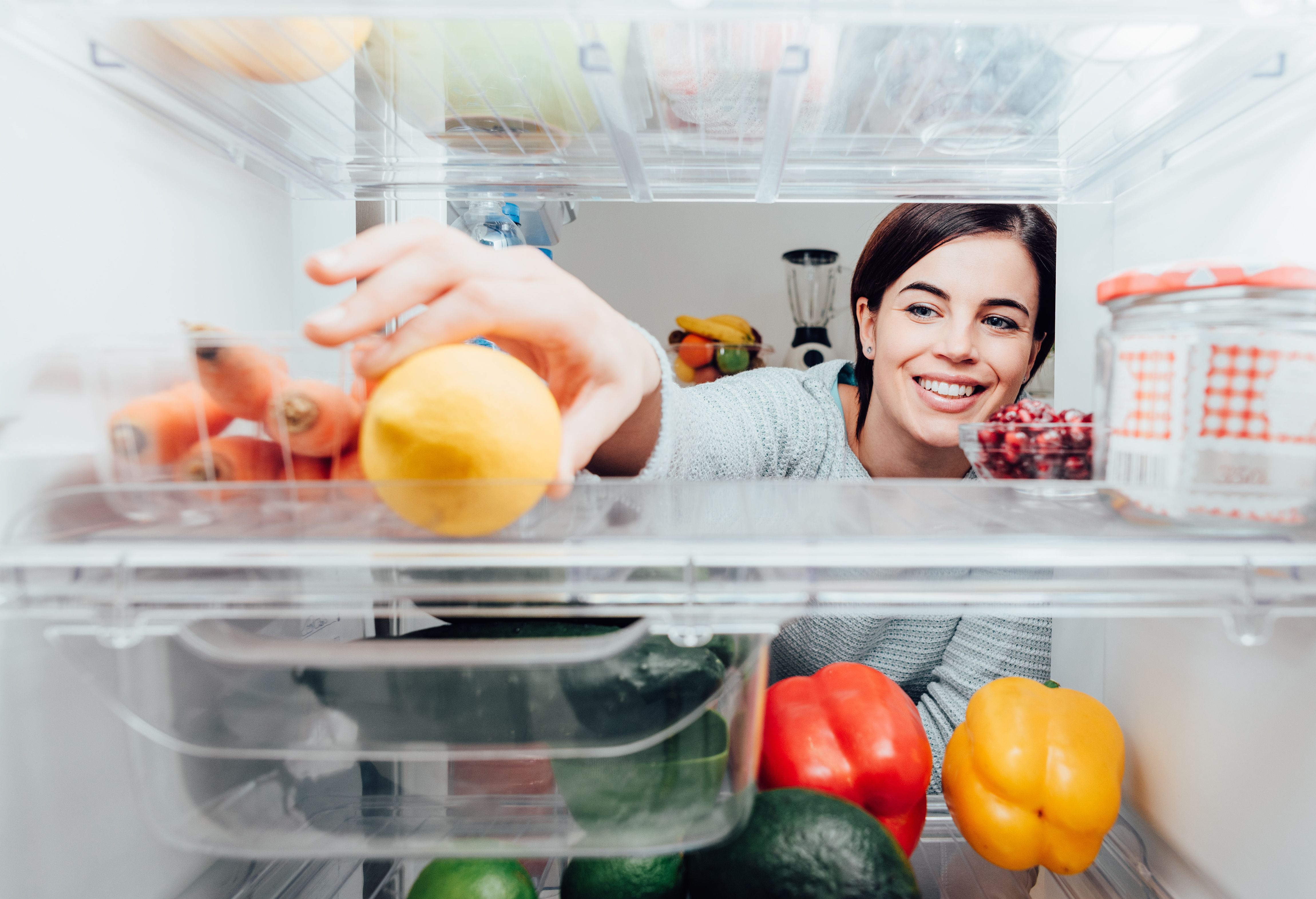 Una mujer abre el frigorífico y está ordenando los alimentos en los estantes