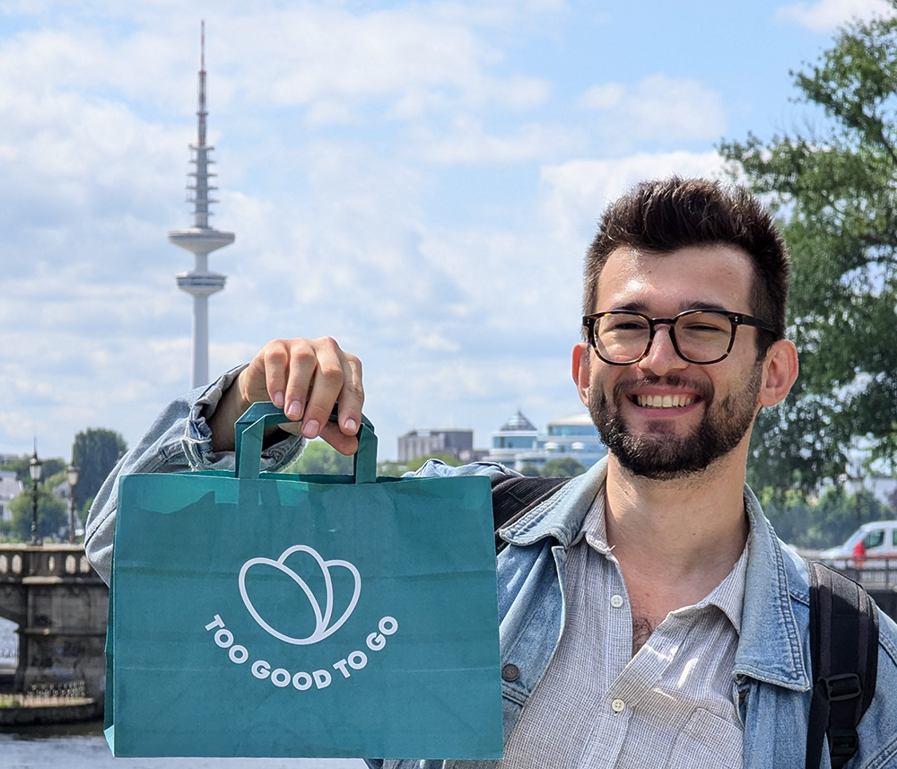 a man holding a bag that says too good to go