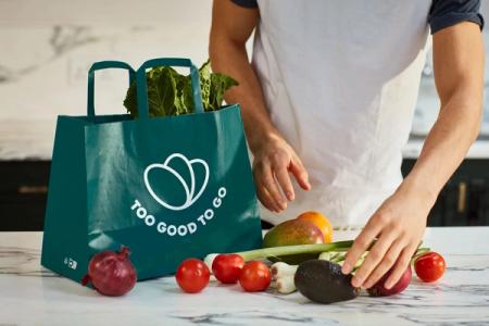 a man is putting vegetables in a bag on a counter .