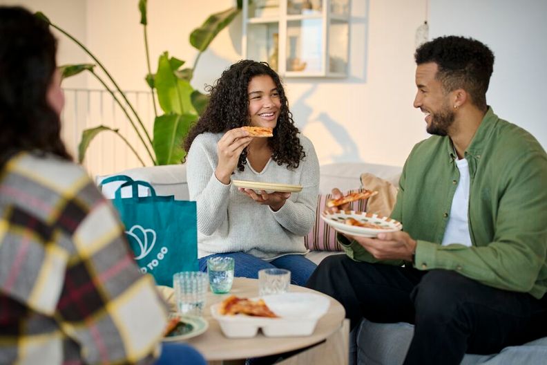 Customers eating pizza from a Too Good To Go bag