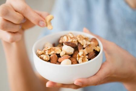 A person is holding a bowl of nuts in their hands.