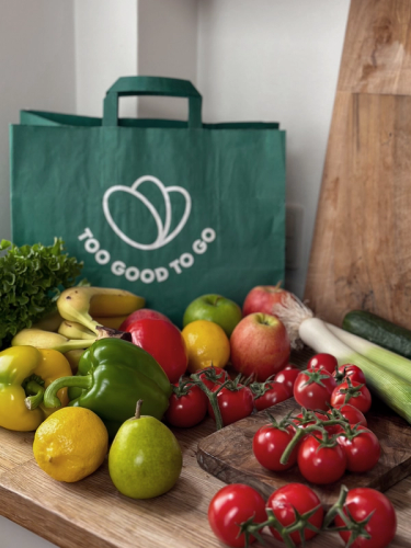 a green too good to go bag surrounded by fruits and vegetables