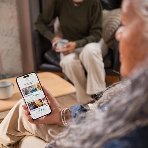 a woman is sitting on a couch looking at her phone .