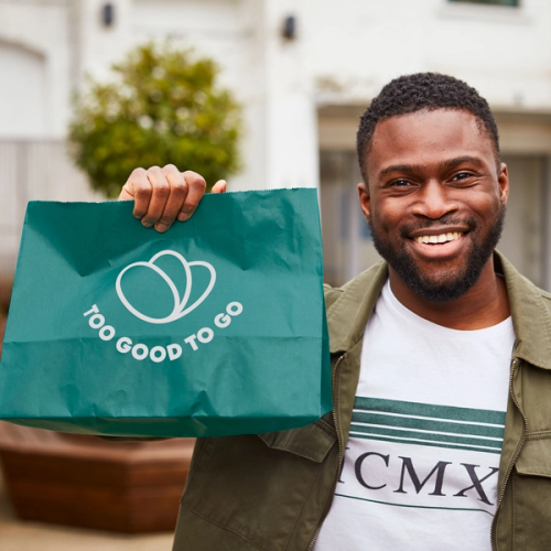 a man holding a green bag that says too good to go