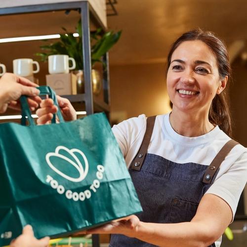 a woman is giving a bag of food to another woman in a bakery .