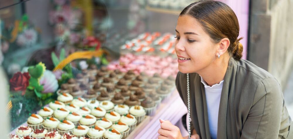 Une femme qui scrute les produits d'une pâtisserie à travers la vitrine