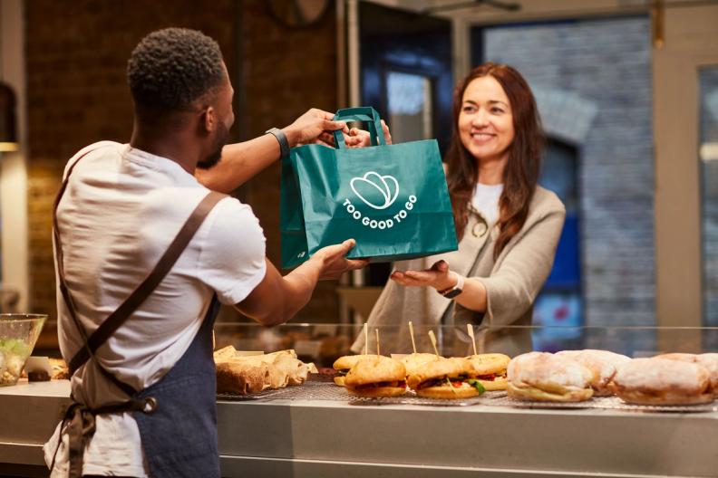 a man is giving a woman a bag of food in a restaurant .