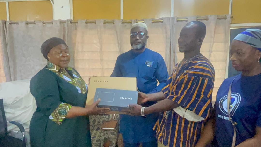 Starlink handover ceremony with community elder in smock and KAPAW staff, Wa