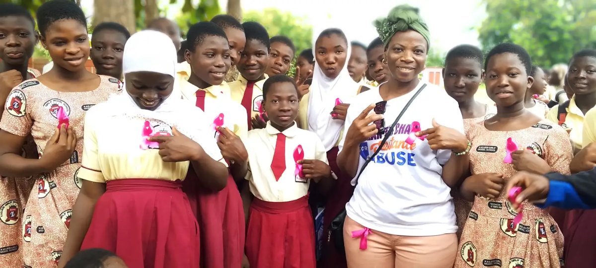Girls at Kadjebi Girls Model School holding pink ribbons at a substance abuse awareness event