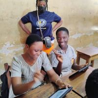Girls smiling while learning on a tablet