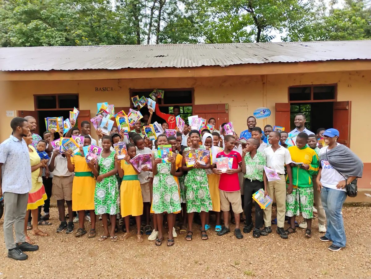 Large group of students holding up donated books at BASIC 8 school