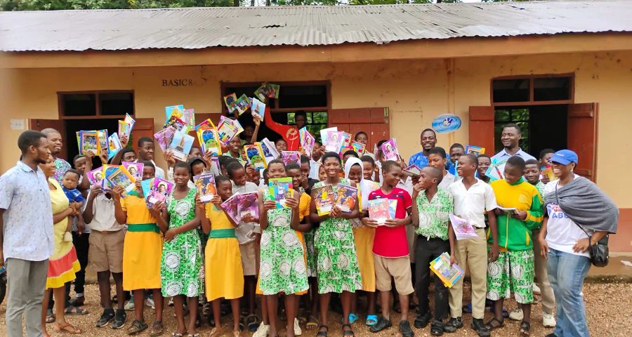 Students holding donated books at a KAPAW book donation event
