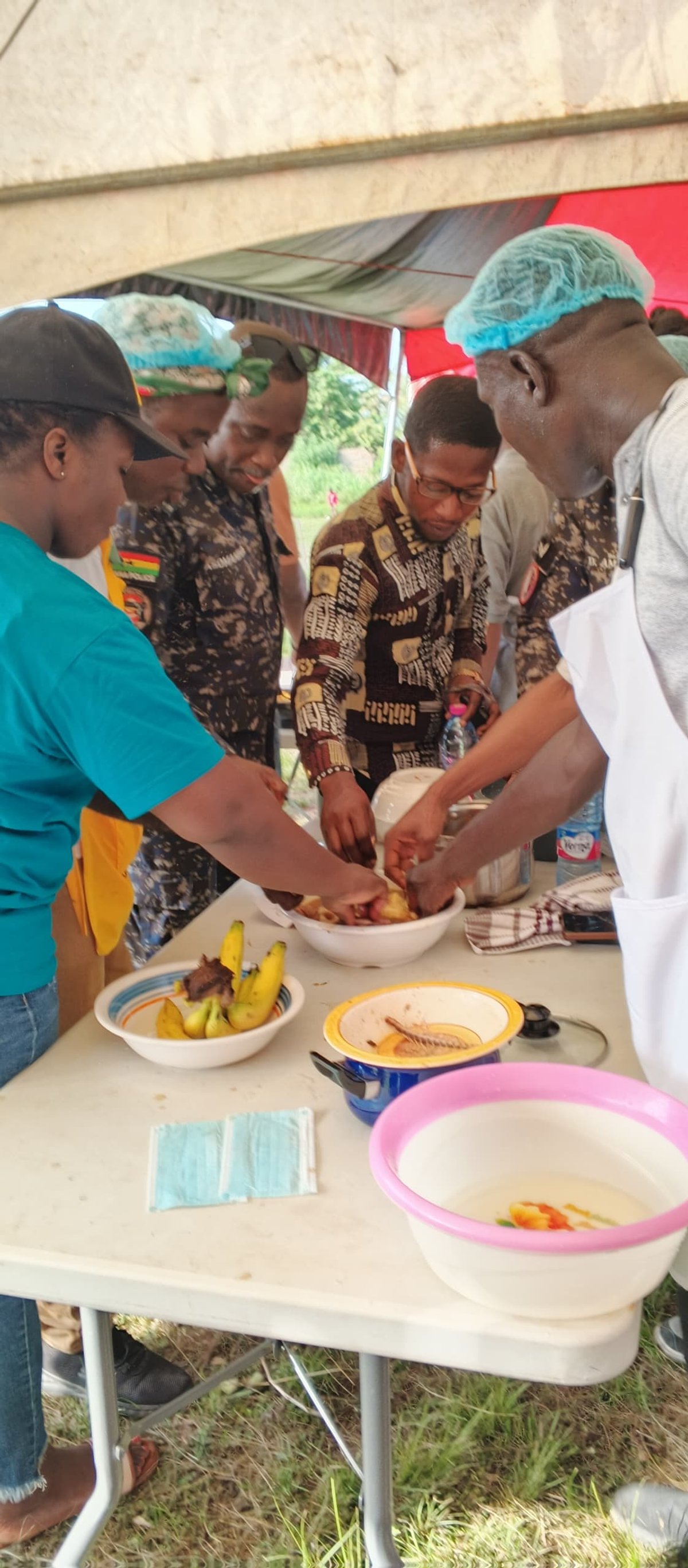 Police officer and community officials at a food preparation station during a community event