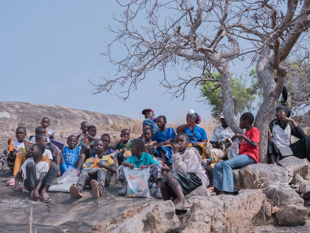 Children resting on rocky terrain at Uombo Rock with KAPAW facilitators