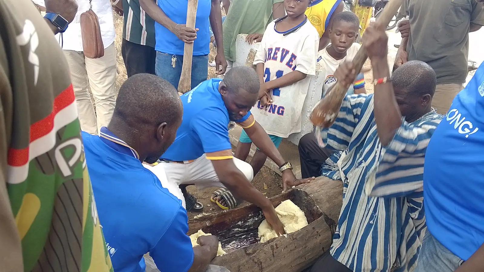 Community members pounding in a traditional wooden mortar at a community livelihoods event