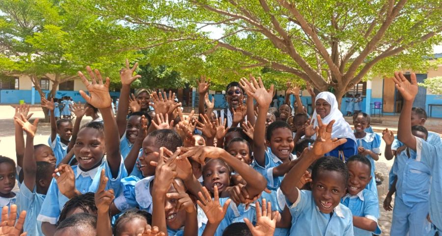 Children joyfully raising hands at a KAPAW community gathering