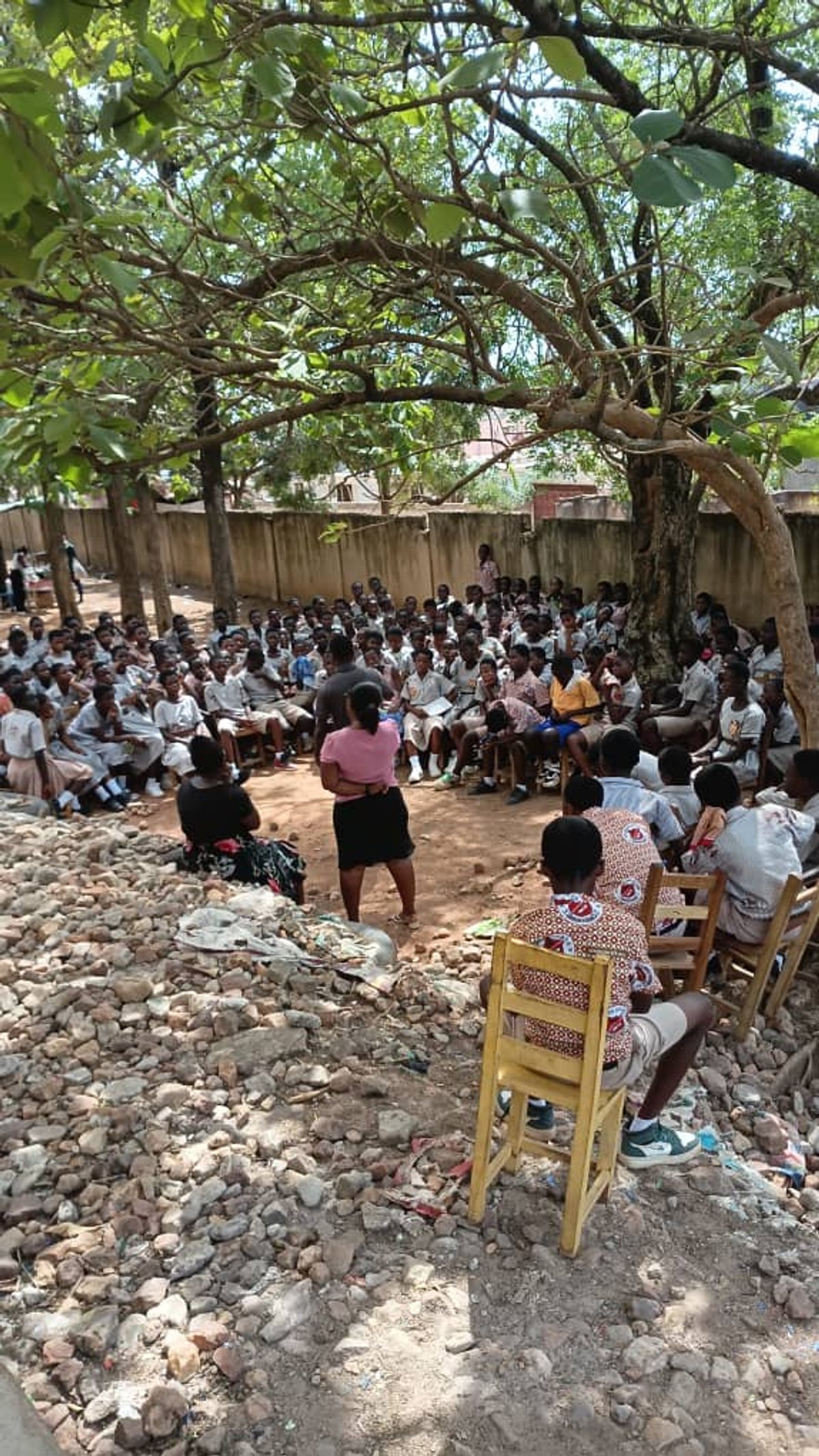 Large group of students gathered under trees for career guidance talk