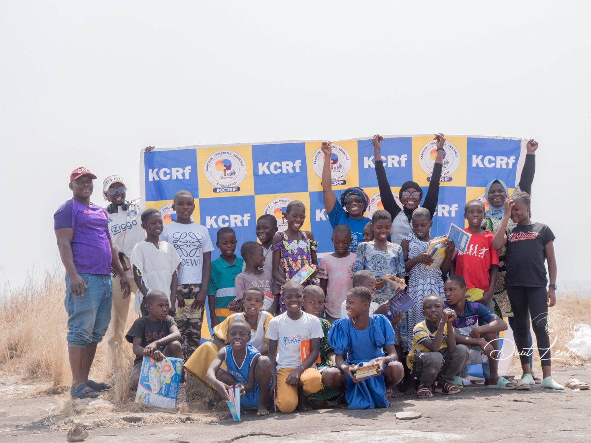 Group photo with KCRf banner at Uombo Rock outing, children holding books and gifts