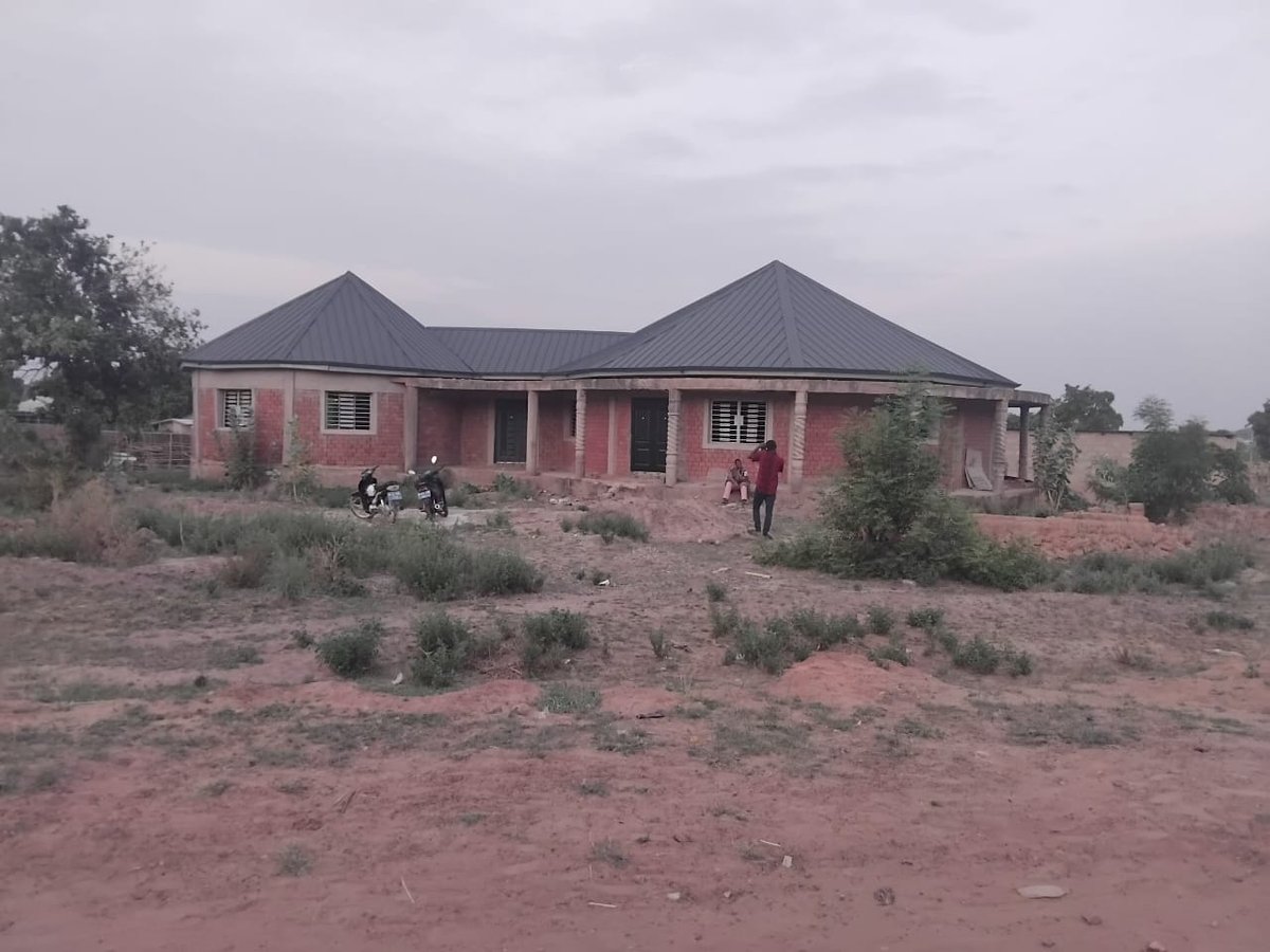 Community building under construction with brick walls and metal roof, Upper West Region