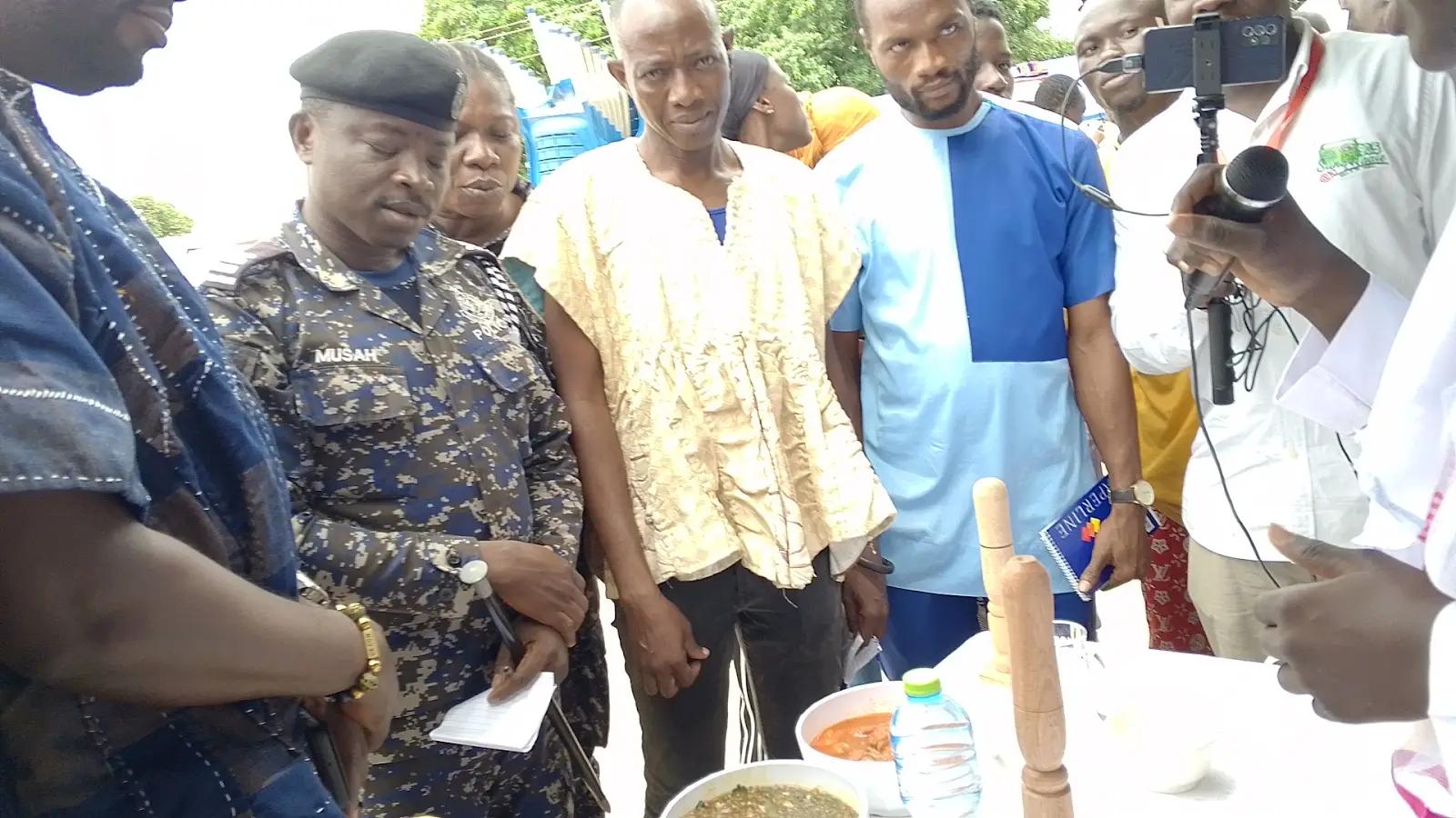 Police officer and community officials watching a food preparation demonstration at a community event
