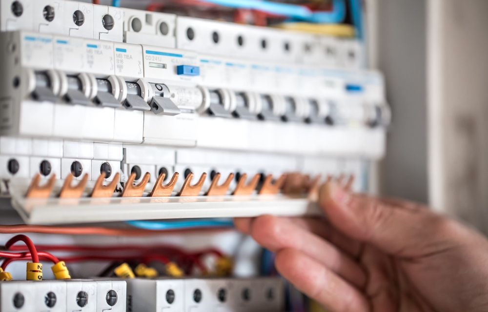 Homeowner safely turning off the main electrical fuse box to prevent electrical hazards during a plumbing emergency.