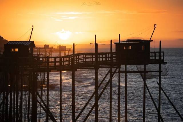 Carrelets en silhouette devant un coucher de soleil sur l’eau