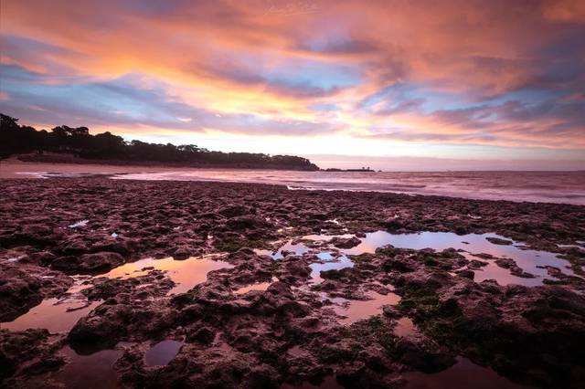 Rochers et mares reflétant un ciel rose et orangé au Platin