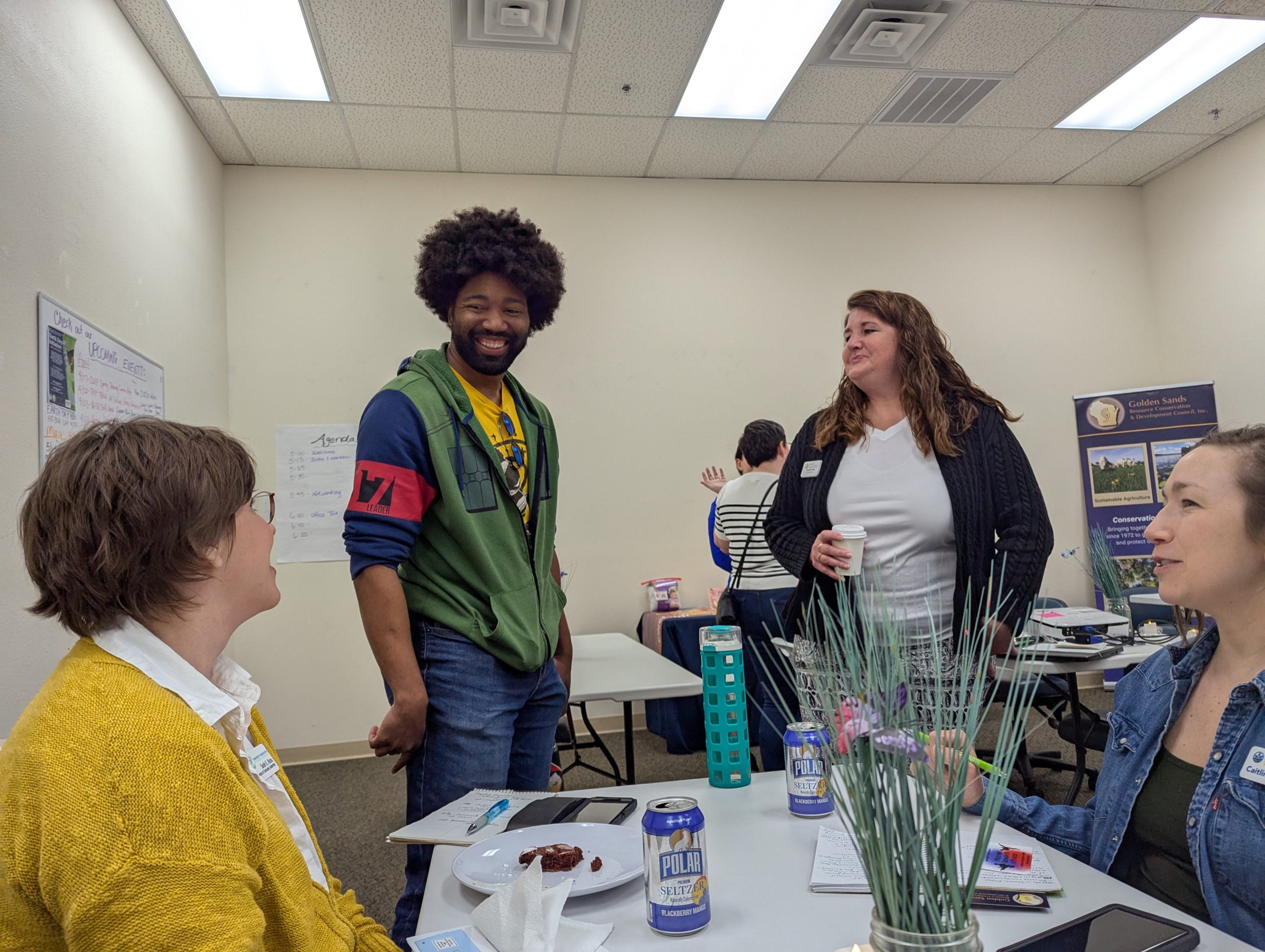 Four people laughing together around a table at a nonprofit gathering in Stevens Point.