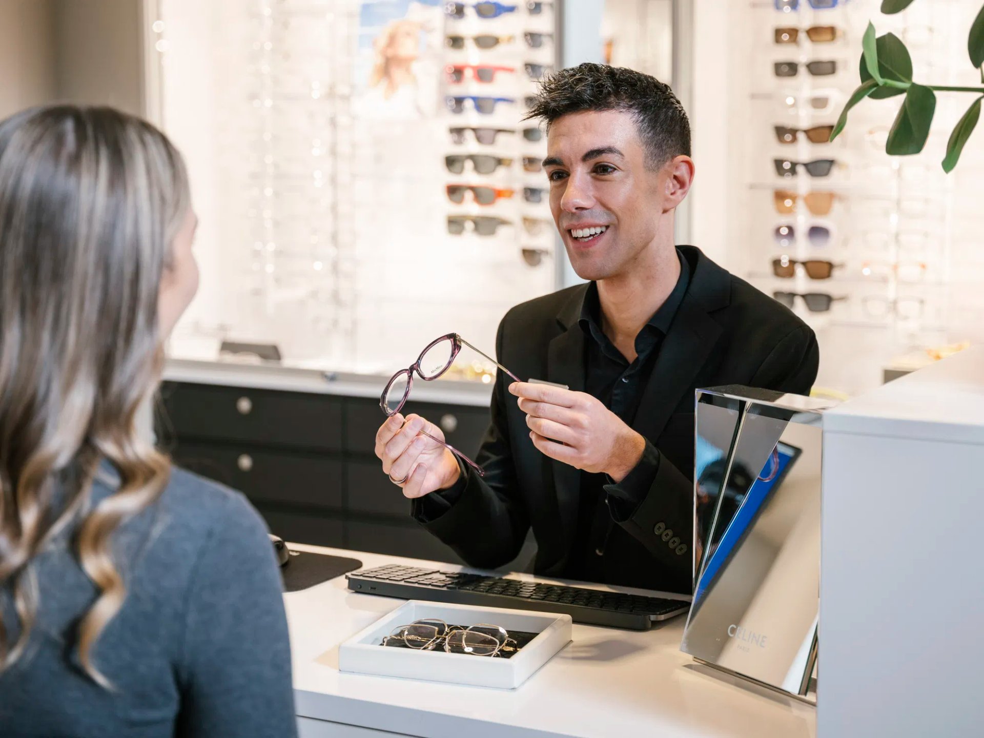 Optiker viser fram en brille til en kunde i butikken
