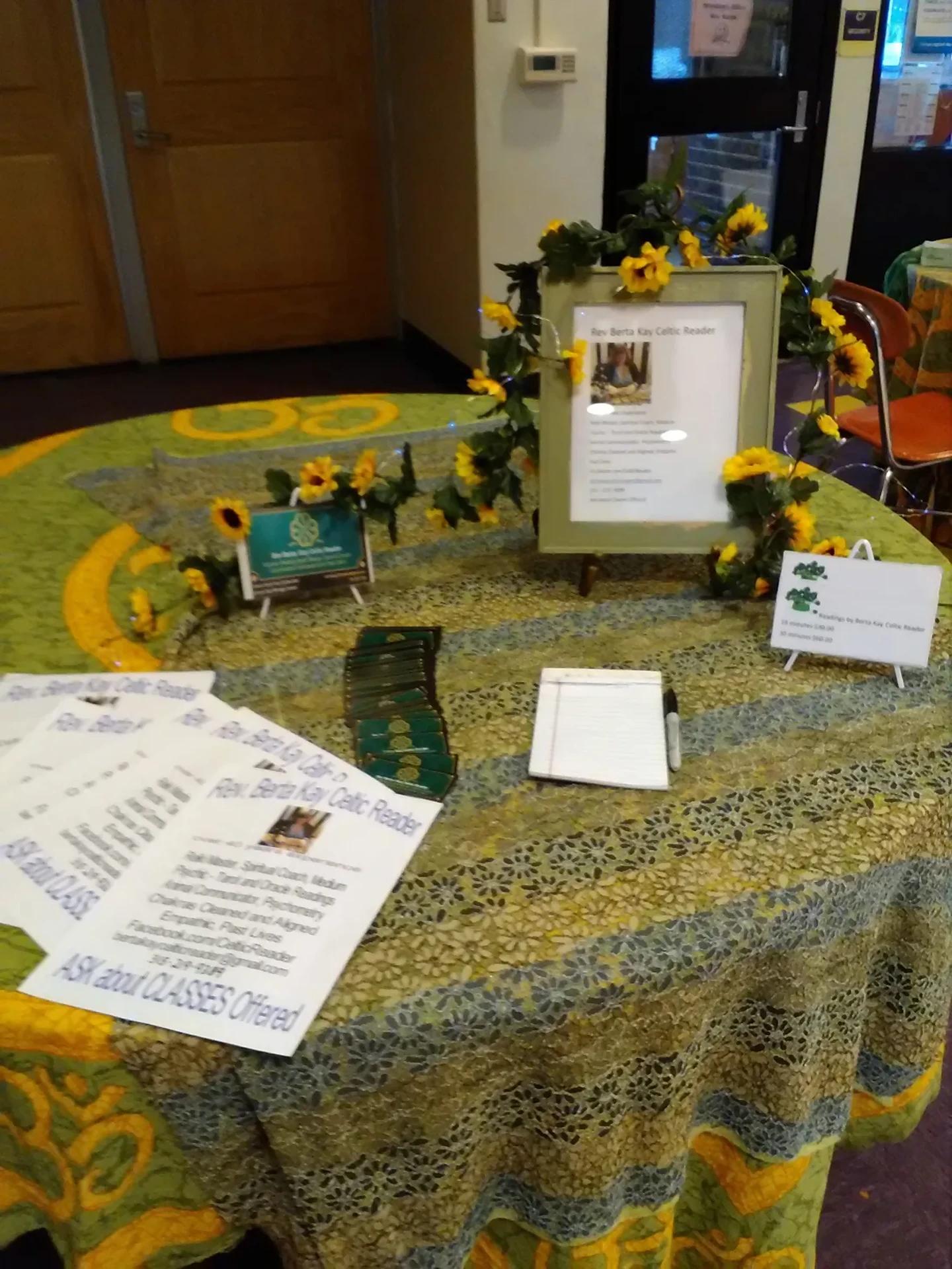 Psychic fair reading table decorated with green cloth and bright sunflowers