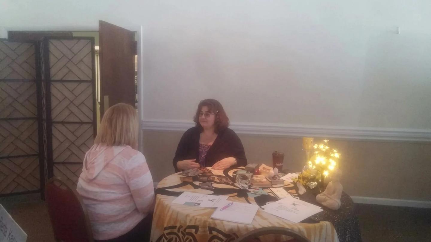 Rev. Berta Kay giving a private in-person psychic reading across a round table