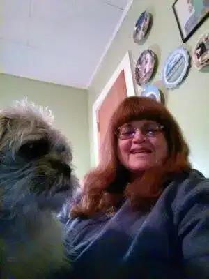 Rev. Berta Kay smiling beside a small fluffy dog
